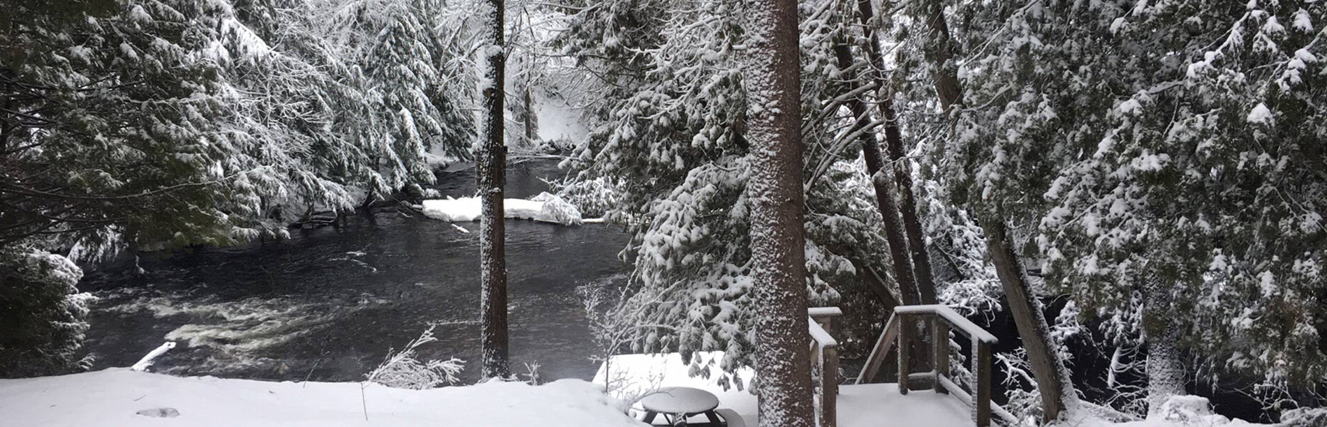 A wintery river rushes amongst freshly fallen snow.