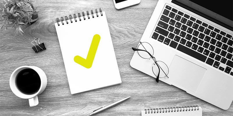 A list with checkmark among a desktop with a laptop and other items.